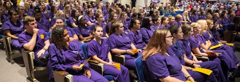 Students in purple scrubs seated in an auditorium