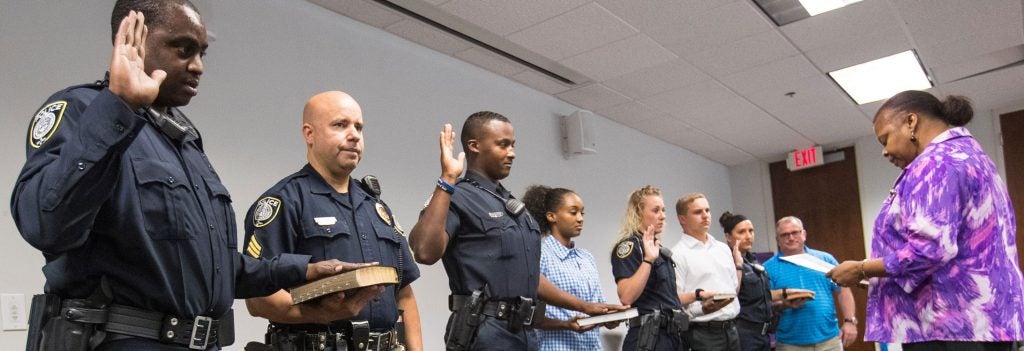 Group of police officers in uniform. Each one has their left hand on a bible, and their right hand raised.